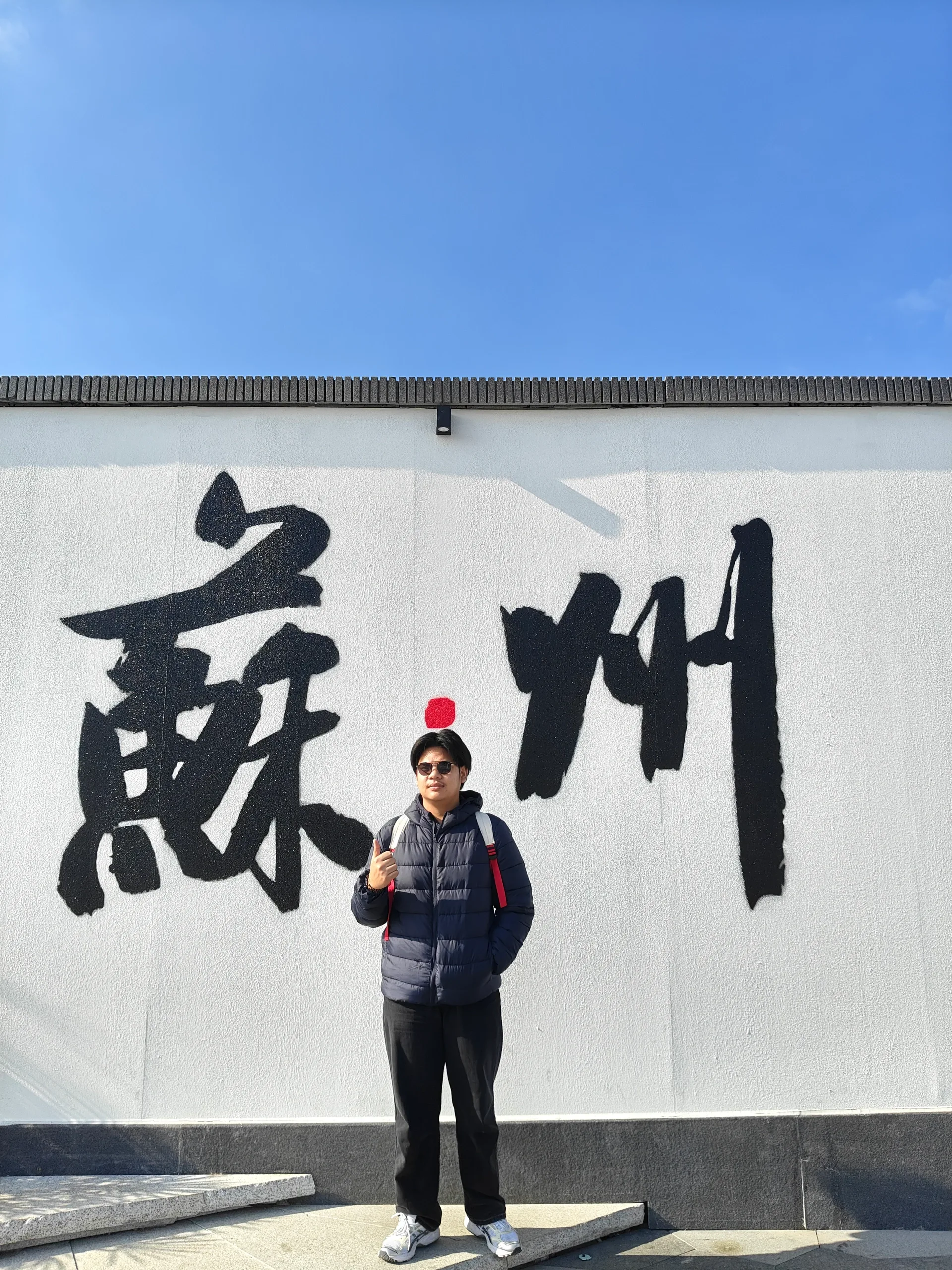 A travel portrait in front of a Suzhou sign
